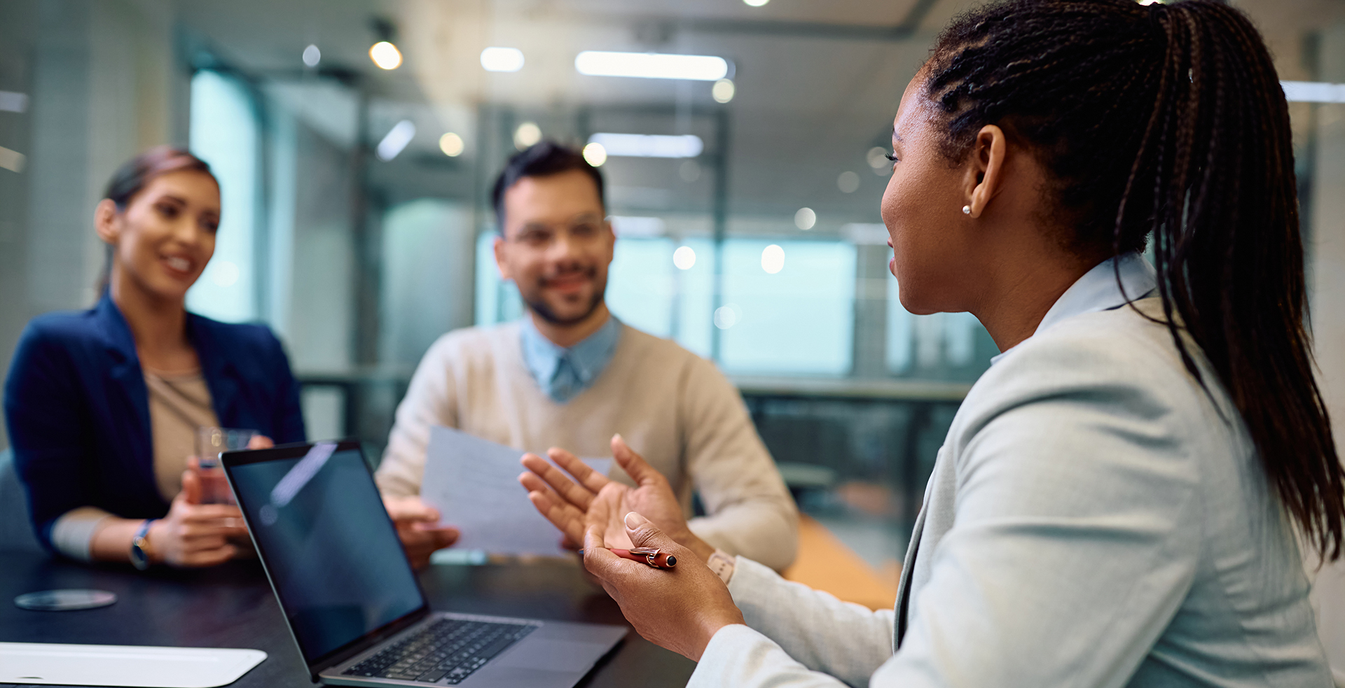 Black female financial advisor talks to couple during meeting in office.